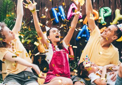 Joyful family with children throws air balloons and golden confetti Joyful family with children throws air balloons and golden confetti